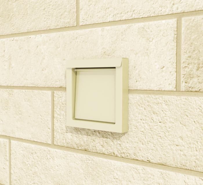 DryerWallVent in tan installed in a stone wall.